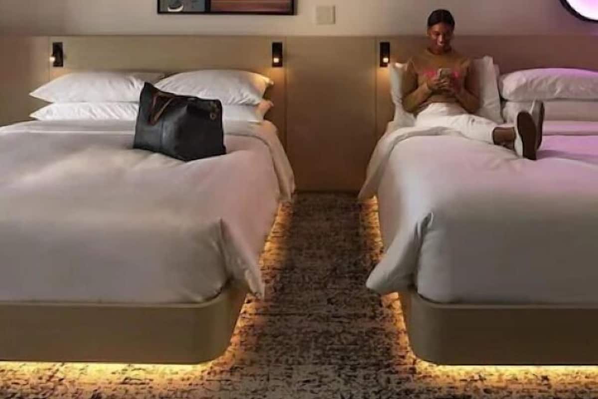 A hotel room with two beds, a carpeted floor, and artwork on the wall.