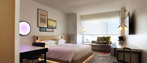 Een moderne hotelkamer met een groot bed, een bureau, een stoel, een klein tafeltje, een rode kruk en een koffer.