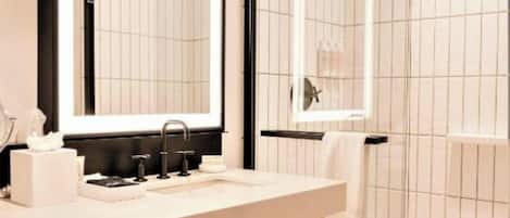 A modern bathroom with a large mirror, a sink, and a glass-enclosed shower.
