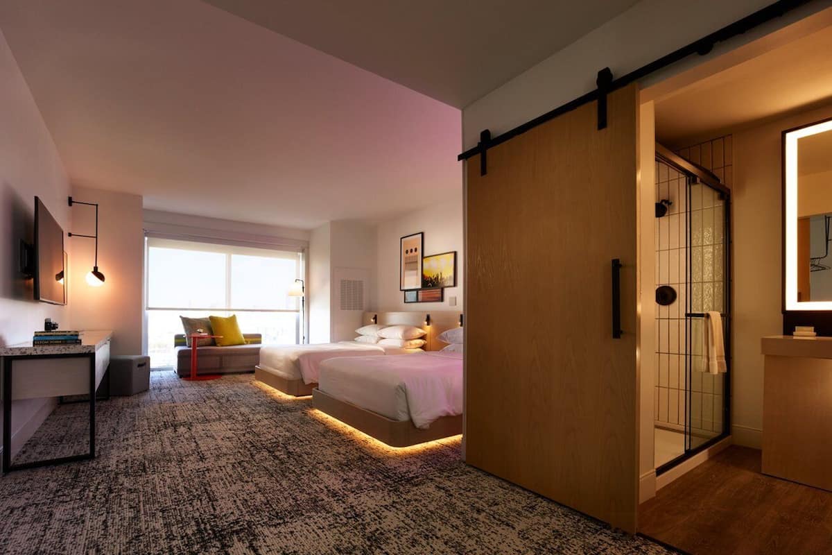 A modern bedroom with a large bed, a desk, and a walk-in closet.