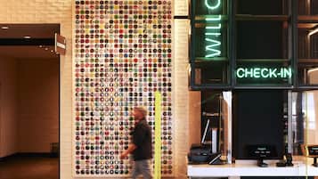A lobby with a wall of colorful bottle caps, a check-in counter, and seating area.