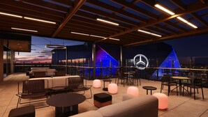 An outdoor seating area with modern furniture, a large illuminated logo, and a view of the sunset. - Reverb by Hard Rock Downtown Atlanta (Atlanta)