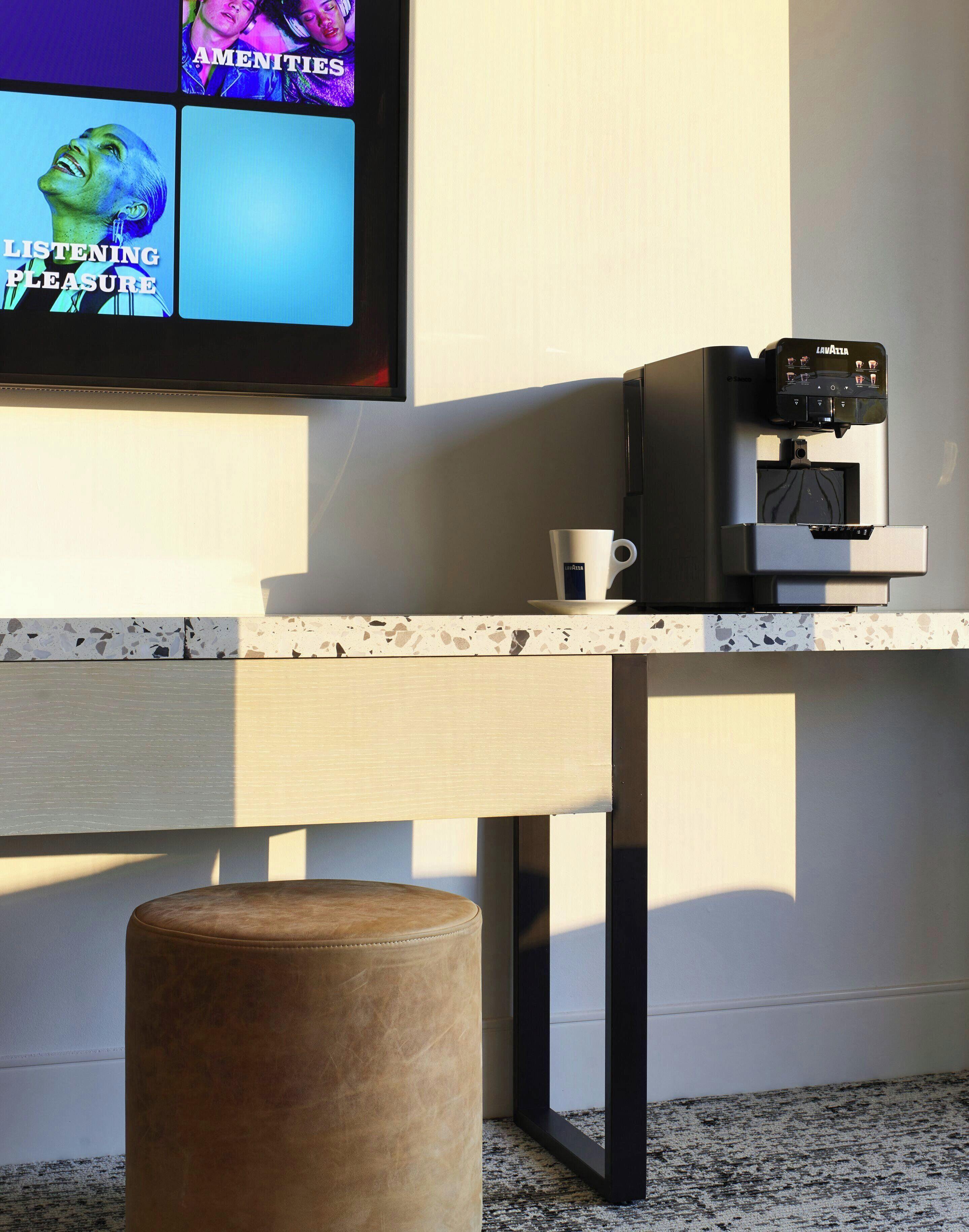 Una cucina moderna con una macchina del caffè, una tazza e un televisore che mostra musica.