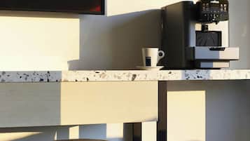 Una cucina moderna con una macchina del caffè, una tazza e un televisore che mostra musica.