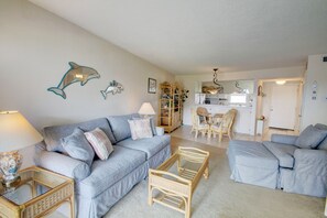 A living room with a sofa, a coffee table, and a bookshelf. - El Matador 235 - FREE TICKETS!! Your stay includes free tickets to many area attractions! (Fort Walton Beach)