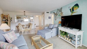 Un salon comprenant un canapé, un téléviseur et une console sur laquelle sont disposés des objets décoratifs.