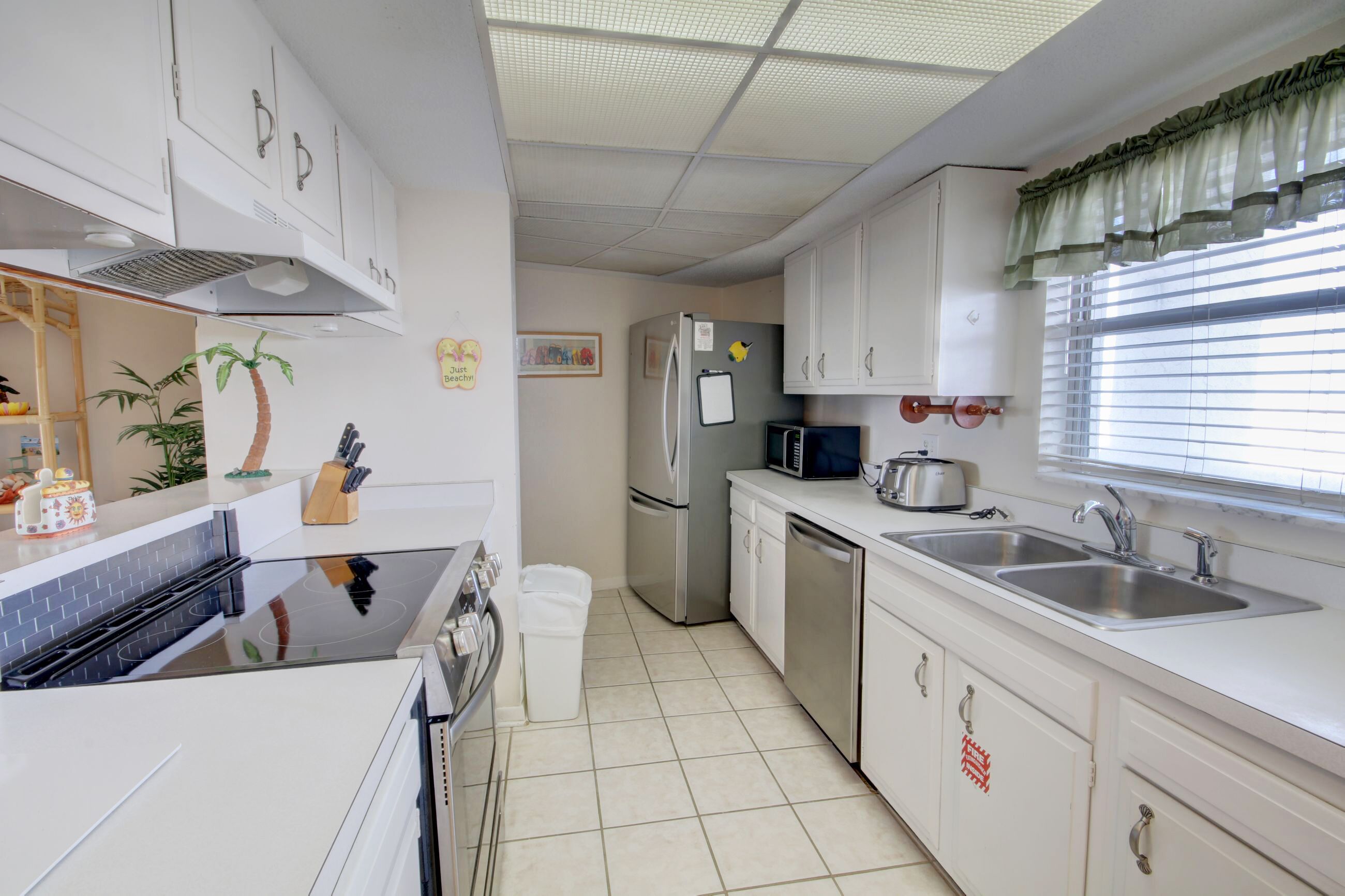 Una cocina compacta con armarios blancos, un microondas, un refrigerador, un lavamanos y una estufa.