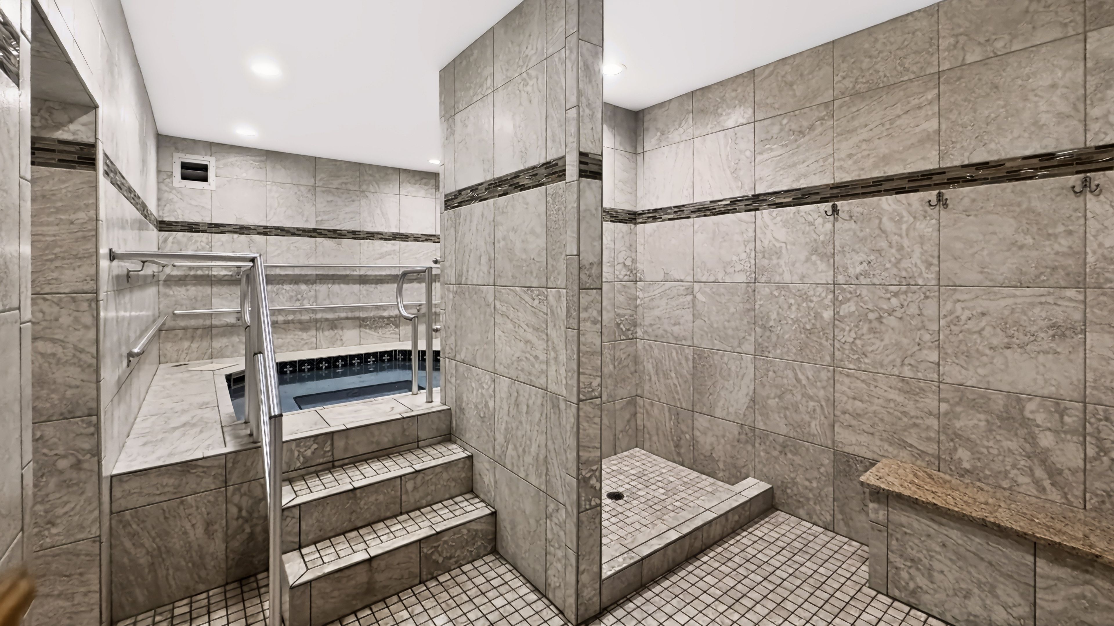 A modern bathroom with a marble floor, a built-in shower, and a glass-enclosed jacuzzi.
