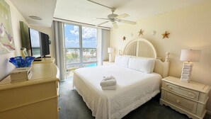 A hotel room with a large bed, a ceiling fan, a TV, and a view of the ocean. - El Matador 444 -  FREE TICKETS!! Your stay includes free tickets to many area attractions! (Fort Walton Beach)
