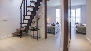 A modern apartment with a wooden staircase, a small table with a plant, and a bed with a view of the outdoors. - Havana - house with pool in Playa de Alcudia (Alcúdia)