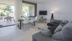 A modern living room with a dining area, a sofa, a TV, and a lamp. - Havana - house with pool in Playa de Alcudia (Alcúdia)
