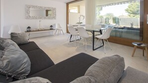 A modern living room with a sofa, a dining table with chairs, a large mirror, and a view of the outdoors. - Havana - house with pool in Playa de Alcudia (Alcúdia)
