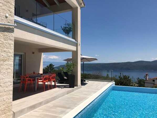 Enjoy a tranquil view of the lake from the balcony, with a swimming pool and dining area nearby.