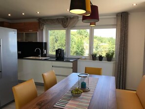 Enjoy meals in the kitchen and dining area with a stainless steel refrigerator, black range hood, and wooden table.