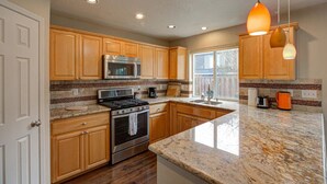 A modern kitchen with wooden cabinets, stainless steel appliances, and a large island. - Modern home in Orenco (Hillsboro)