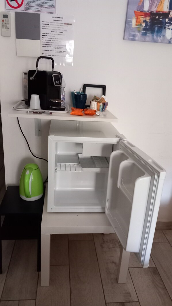 A kitchen area with a refrigerator, a coffee machine, and a kettle. - Comeacasa (Salerno)