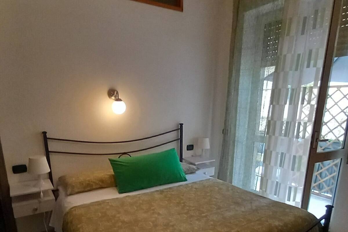 A bedroom with a bed, bedside tables, a lamp, and a window with curtains.