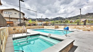 Una piscina con un muro de piedra y vistas a montañas al fondo.