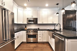 A modern kitchen with stainless steel appliances, white cabinetry, and a wooden floor. - Blackstone 2BR/2.5BA | Two King Suites | Pool & Hot Tub | Canyons Village (Park City)
