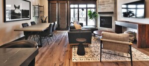 Una sala de estar moderna con comedor, chimenea y un ventanal grande.