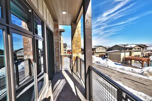 A corridor with large windows, stone walls, and a view of a snowy landscape. - Blackstone 2BR/2.5BA | Two King Suites | Pool & Hot Tub | Canyons Village (Park City)