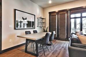 A modern living room with a dining area, a large window, and a sliding glass door. - Blackstone 2BR/2.5BA | Two King Suites | Pool & Hot Tub | Canyons Village (Park City)