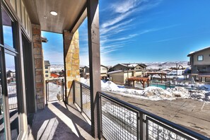 A balcony with a view of a snowy landscape and a pool area. - Blackstone 2BR/2.5BA | Two King Suites | Pool & Hot Tub | Canyons Village (Park City)