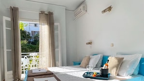 Un dormitorio con cama, mesitas de noche, una ventana con cortinas y un balcón con barandilla.