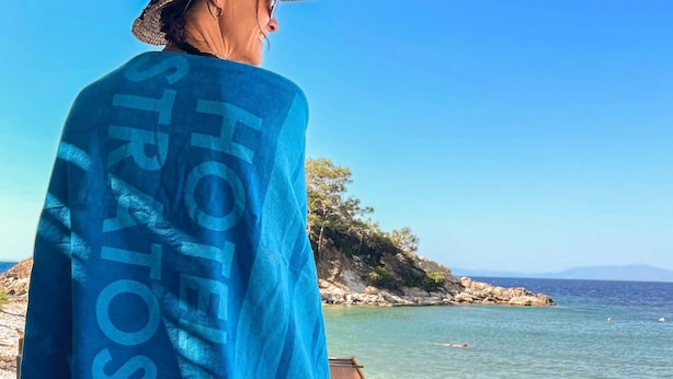 Una playa con aguas azul turquesa, un promontorio rocoso y sillas de descanso.