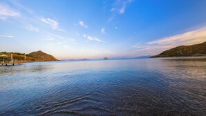 A calm lake with a dock and a boat, surrounded by hills and clear skies. - Mare Garden Hotel Akyarlar (Bodrum)