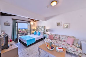 Un dormitorio con cama, sofá, una mesa con fruta y vistas al mar.