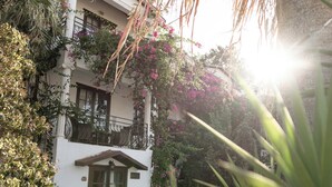 A white building with a balcony, surrounded by greenery and a palm tree. - Mare Garden Hotel Akyarlar (Bodrum)