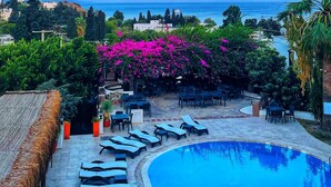 A pool area with lounge chairs and a view of the sea. - Mare Garden Hotel Akyarlar (Bodrum)