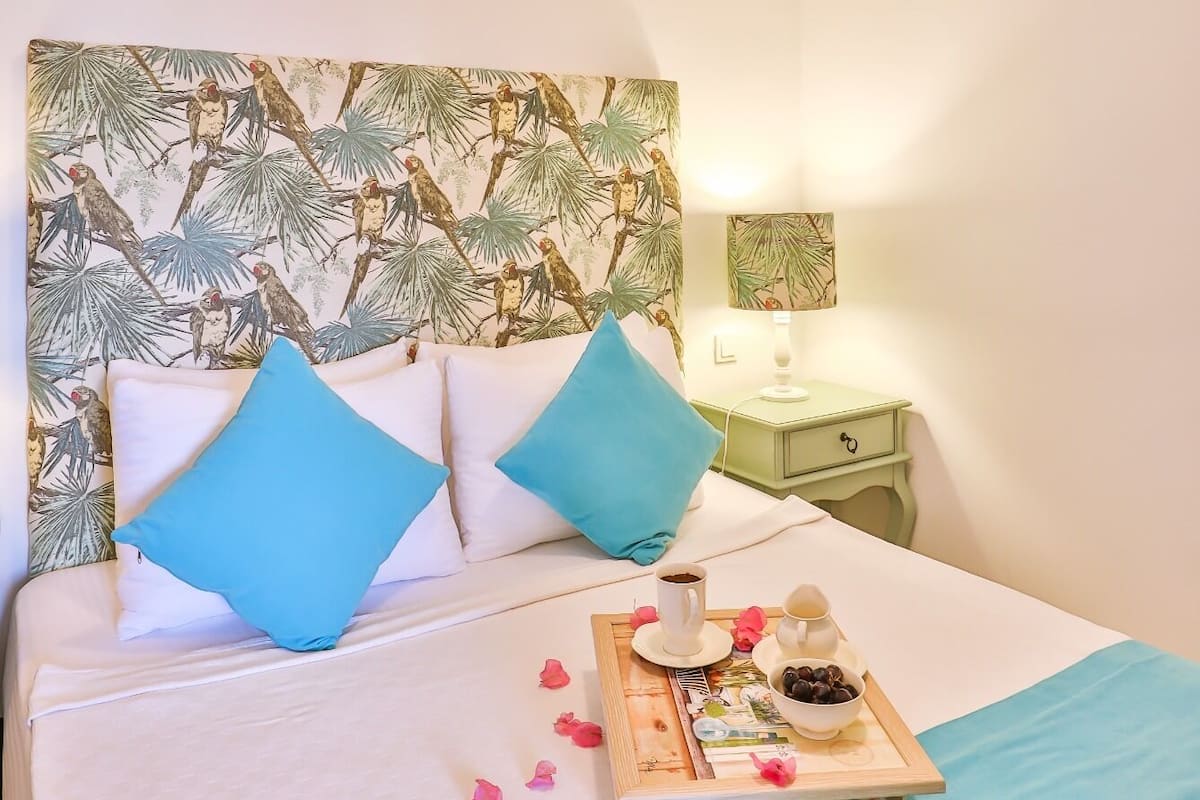 A hotel room with a bed, a nightstand, a wall-mounted air conditioner, and a decorative headboard.