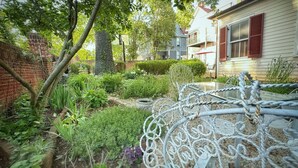 A garden with a metal fence, various plants, and a brick wall. - Whole House Rental in Virgina (Lynchburg)