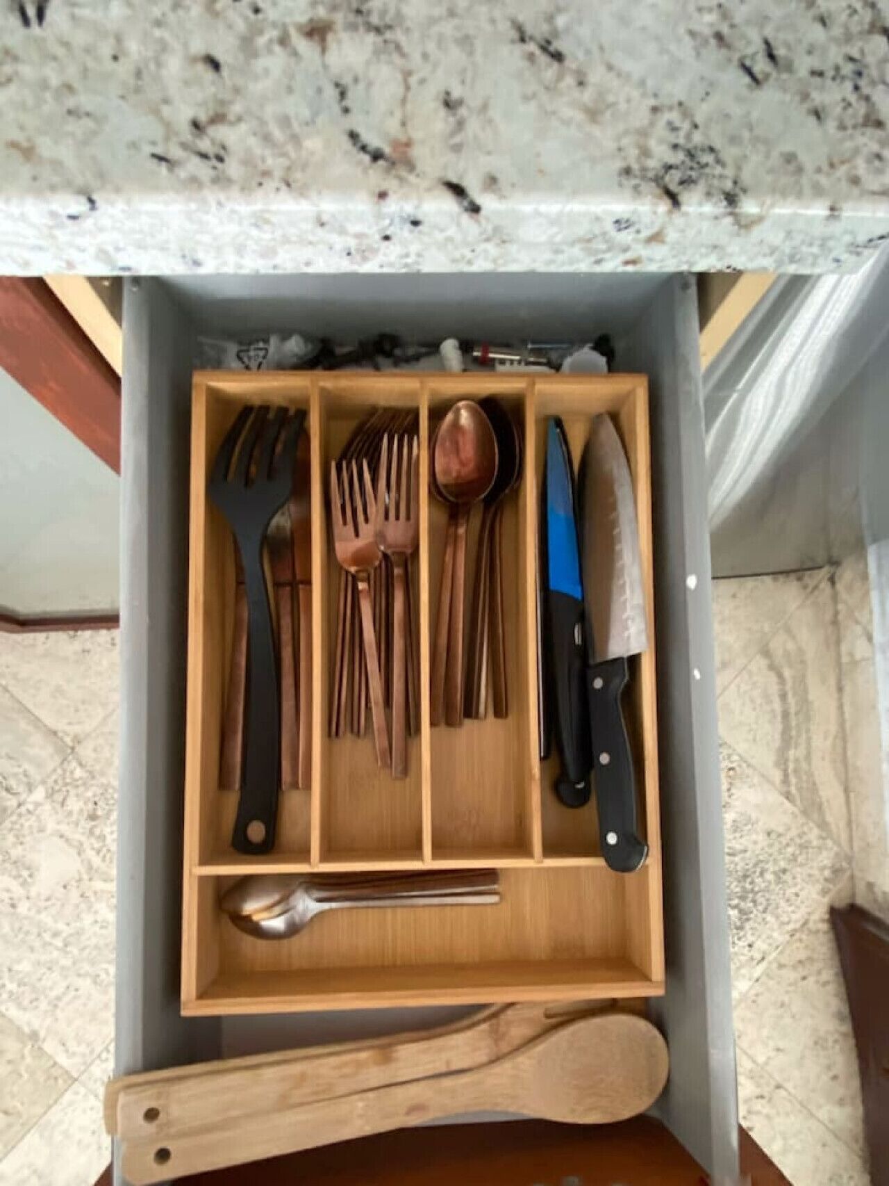 Un cajón con utensilios de madera, como una cuchara, un tenedor y un cuchillo.