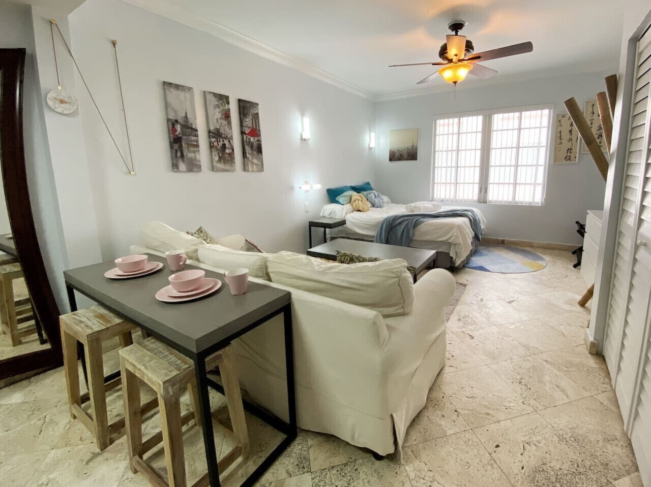 A cozy room with a dining table, two sofas, a ceiling fan, and artwork on the walls.