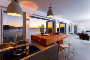 Enjoy expansive sea views from this open-plan living space with a large island and sleek stovetop.