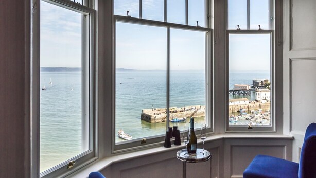 Una habitación con amplias ventanas que dan a un puerto, con vistas a barcos y un muelle.