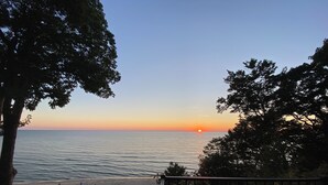 Ein Strand mit Sonnenuntergang, Bäumen und einer Geländer.