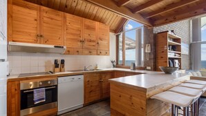Uma cozinha moderna com armários de madeira, eletrodomésticos de aço inoxidável e uma ilha grande com banquetas.