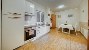 Una cocina moderna con armarios blancos, horno empotrado, microondas y un comedor con mesa y sillas.