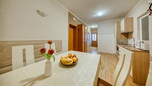 Una cocina moderna con armarios blancos, encimera de madera y una zona de comedor con una mesa para dos.
