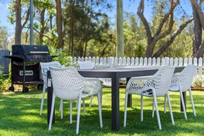 A rectangular outdoor table with a white fence in the background. - Calm Waters Waterfront Cottages @ Sussex Inlet, No. 5 Garden View (Sussex Inlet)