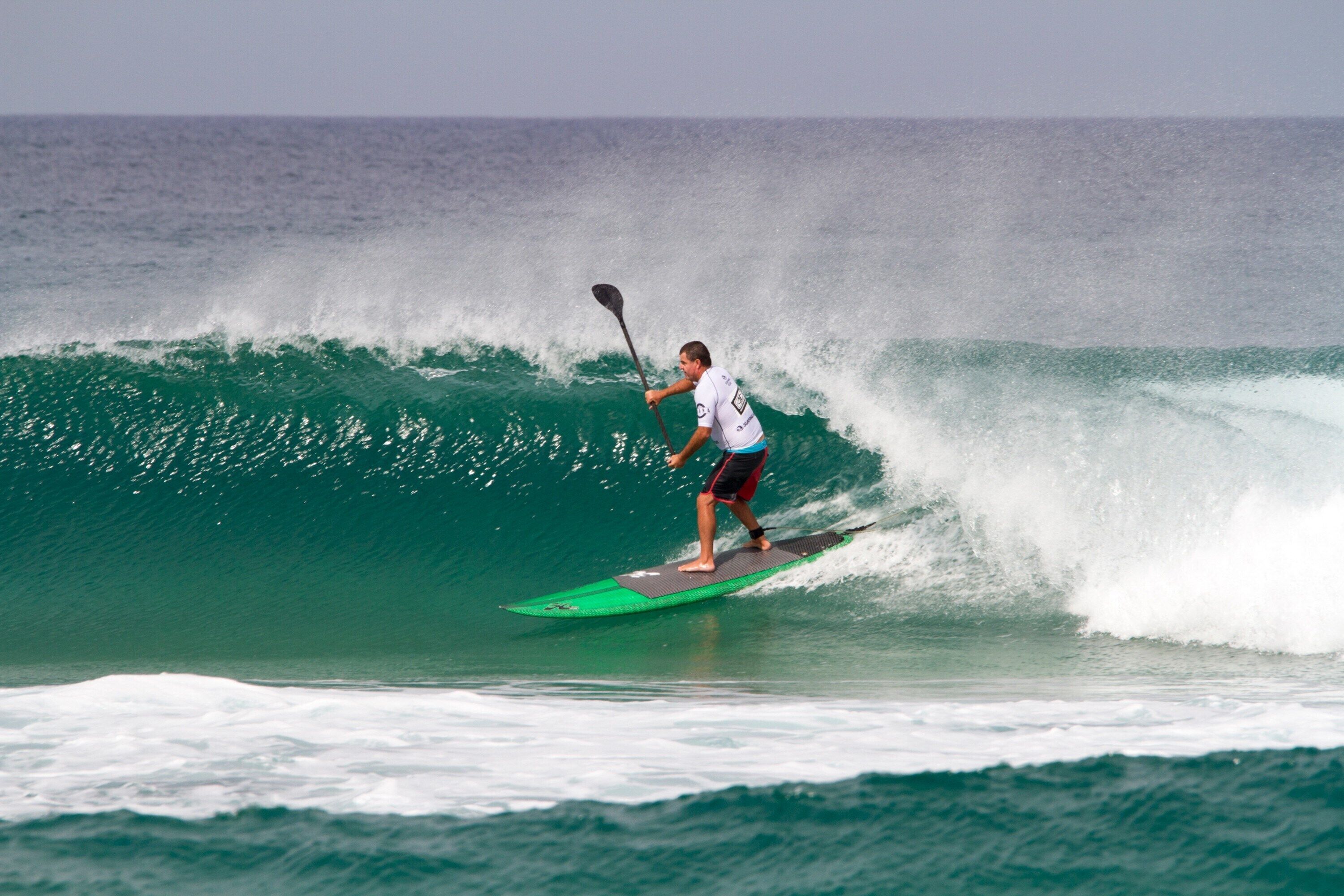 A person surfing on a wave with a paddleboard.