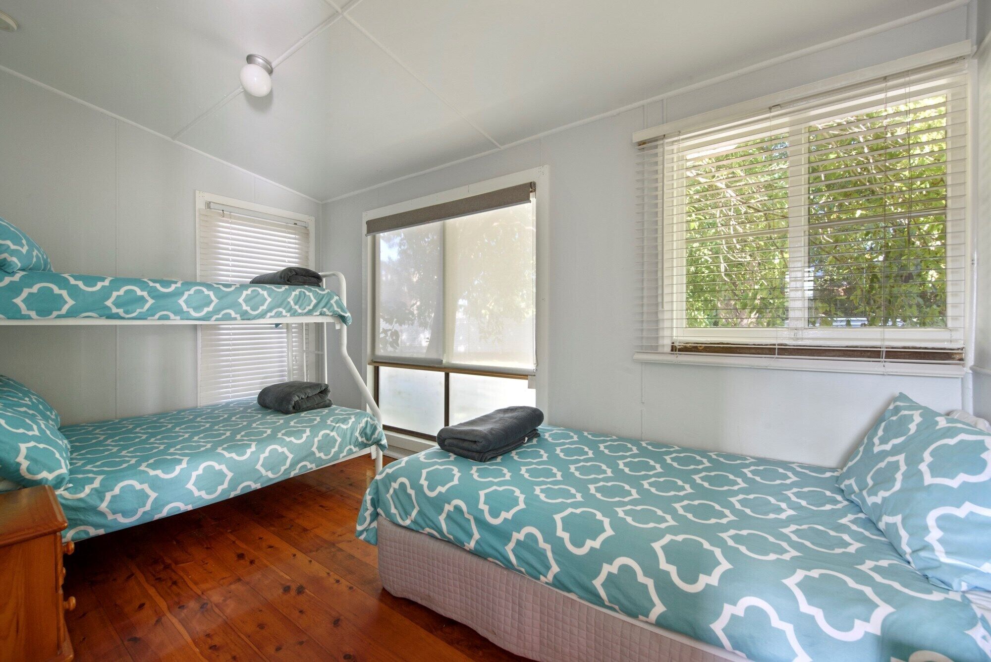 A room with bunk beds, a window with blinds, and a ceiling light.