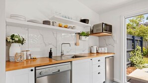 A modern kitchen with a dishwasher, a microwave, and a sink. - Studio Ocean Breeze @ Huskisson (Huskisson)