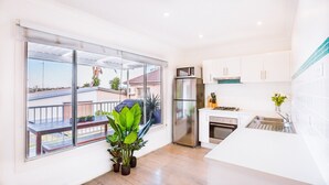 A modern kitchen with a large window, a refrigerator, a stove, and a sink. - Ocean Breeze @ Huskisson (Huskisson)