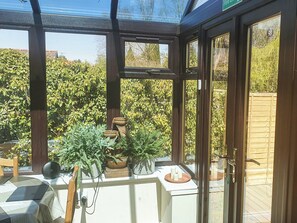 A conservatory with a glass door, wooden beams, and potted plants.