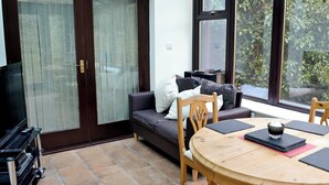 Una sala de estar acogedora con un sofá, una mesa de comedor de madera y un mueble para la televisión.